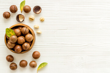 Wooden bowl of shelled macadamia nuts with leaves