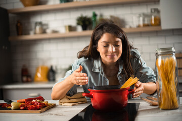 Beautiful pregnant woman preparing delicious food. Smiling woman cooking pasta at home