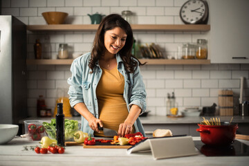 Beautiful pregnant woman preparing delicious food. Smiling woman cooking pasta at home
