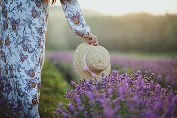 beautiful lavender field, large, blooming, spring mood. a beautiful girl in a hat, stands backwards, a girl runs across the field, in a white and colored dress