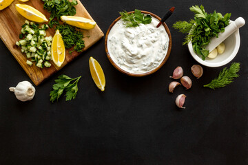 Greek dip sauce sour cream with herbs and cucumber. Cooking on kitchen table