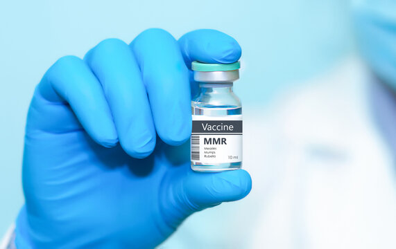 Doctor in protective gloves holding a MMR Measless, Mumps and Rubella diseases vaccine in the children and adolescents. The concept of medicine, healthcare, science and vaccination awareness.