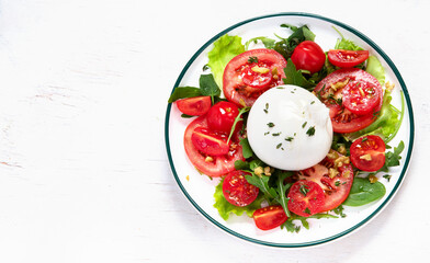 Delicious caprese salad with tomatoes and mozzarella cheese with fresh leaves. Italian food.