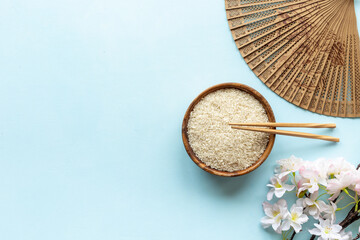 Bowl of rice and asian fan with cherry blossom branch. Asian concept - obrazy, fototapety, plakaty