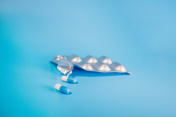 Blue capsules with medicine in a blister pack on a blue background. Treatment. Health concept