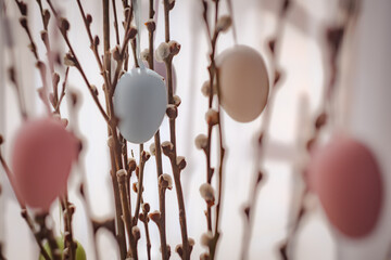 Holidays and object concept. Close up of pussy willow branches decorated by easter eggs over bokeh...
