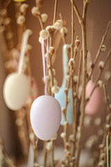 Holidays and object concept. Close up of pussy willow branches decorated by easter eggs over bokeh lights. Vertical photo