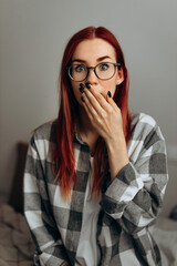 The red-haired woman in the plaid shirt and glasses is very surprised