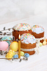 Easter holiday background. Easter sweet cakes, willow, candle, colorful eggs and decorative chicken toy on wooden table close up. festive composition