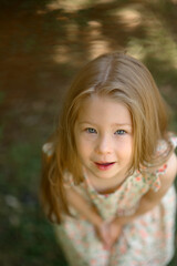 Little girl 3 years old in a summer sundress in the park. Summer time.