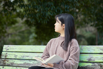 Obraz premium 春の公園で読書しながらコーヒーを飲む女子中学生の姿