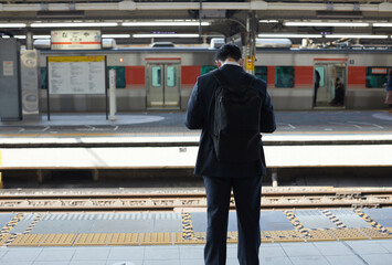 名古屋駅のホームで電車待ちの一人のサラリーマンの後ろ姿