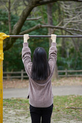 Fototapeta premium 春の公園で鉄棒で運動している女子中学生の後ろ姿