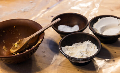 Bowls of rye and wheat flour are on a table in a bakery, close up