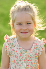 Little girl 3 years old in a summer sundress in the park. Summer time.