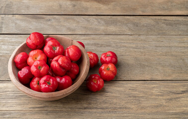 Acerolas or Barbados Cherries on a bowl over wooden table with copy space