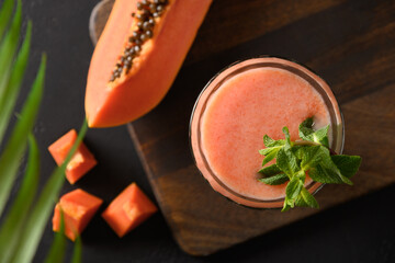 Asian traditional Papaya lassi served with mint on dark background. Freshness cold beverage made of yogurt, water, spices, fruits and ice. Popular beverage in India and Sri lanka. View from above
