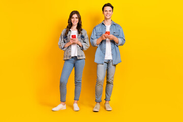 Naklejka premium Full length photo of funky attractive best buddies wear jeans chatting twitter telegram facebook isolated yellow color background