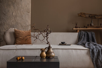 Wabi sabi living room interior with modular sofa, stylish vase with branch, square coffee table, blue plaid, brown pillows, wooden sculpture and personal accessories. Home decor. Template.