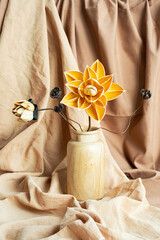 Dried flowers in wooden vase against draper. Monochromatic modern still life.