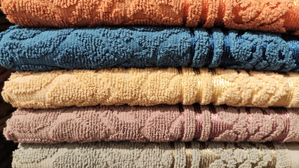 Abstract background and texture from a stack of colored soft terry towels. Lots of colorful bath towels stacked on each other. Cotton towels for hotels, home, bathroom, kitchen