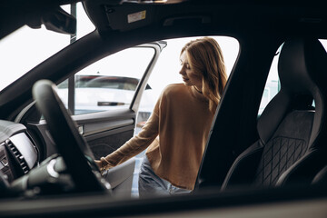 Obraz na płótnie Canvas Woman choosing new car in car showroom