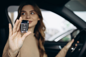 Woman sitting in her new car in car showroom