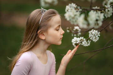 Spring Fairy. A ballerina in a blooming orchard. Beautiful white flowers and blonde girl in ballet dress. 