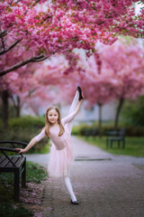 Princess in pink. A little ballerina under the pink trees. Spring flowering sakura. 