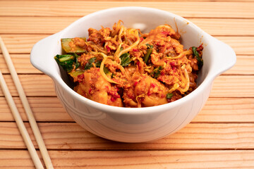 Fried dumplings in a white bowl. Made from wet dumplings that are sauteed with mustard greens, bean sprouts and spicy seasonings