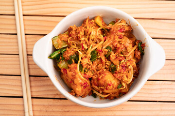 Fried dumplings in a white bowl. Made from wet dumplings that are sauteed with mustard greens, bean sprouts and spicy seasonings