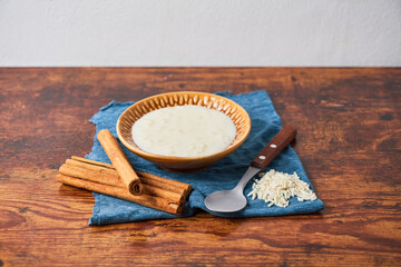 Delicious rice pudding or arroz con leche with cinnamon in bowl on wooden table