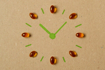 Clock made of omega 3 Fish Oil capsules on recycled paper background - Concept of supplement,...