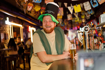 funny ginger man in leprechaun hat for st patrick's day in pub