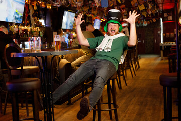 cheerful ginger man in leprechaun hat for st patrick's day in pub