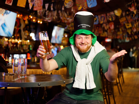 cheerful ginger man in leprechaun hat for st patricks day with beer