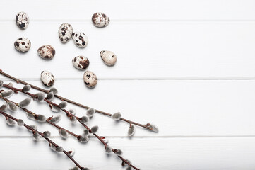 Fototapeta premium Quail eggs and willow branches on a white wooden table. Easter background.