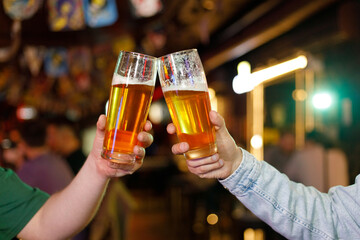 Two friends toasting with glasses of beer at the pub with free space for your text. Beautiful...