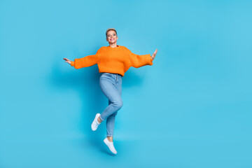 Fototapeta na wymiar Full length photo of cute excited pretty dressed knitted pullover jumping high empty space isolated blue color background
