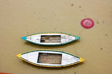 Barcas de colores amarradas en el rio Ganges en la india con el agua marron y muy turbia
