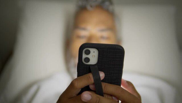 unrecognizable black man using mobile phone at night. Lying down in bed scrolling social media