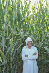 Attractive young farmer smiling standing in corn field.  shallow depth of field, follow focus, blur.