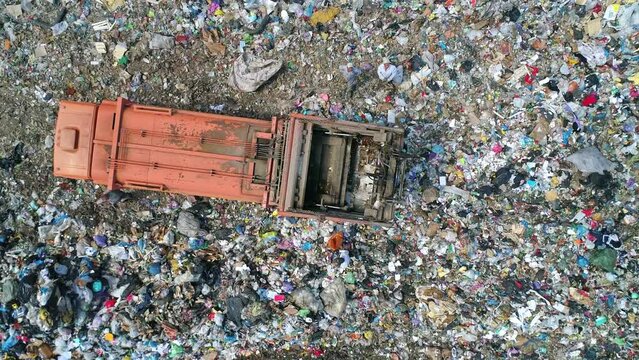 Aerial top down view of truck unloading garbage, waste at landfill. Trash truck dump waste products polluting in an trash dump.