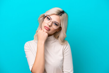 Young Russian woman isolated on blue background With glasses and with sad expression