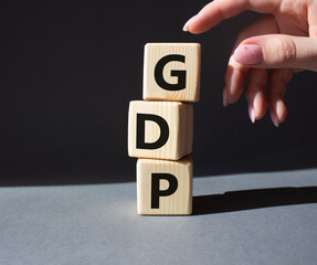 GDP - Gross domestic product symbol. Concept word GDP on wooden cubes. Businessman hand. Beautiful grey background. Business and GDP concept. Copy space.