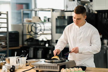 A professional chef in the kitchen of a restaurant prepares pancakes for breakfast. Culinary recipe Frying pan on the stove