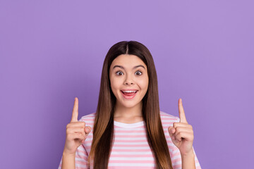 Photo of charming impressed girl dressed striped white pink t-shirt pointing up empty space isolated purple color background