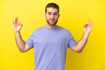 Handsome blonde man over isolated yellow background in zen pose