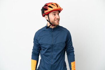 Young cyclist man isolated on white background thinking an idea while looking up