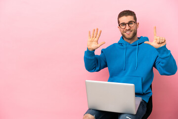 Young man sitting on a chair with laptop counting seven with fingers